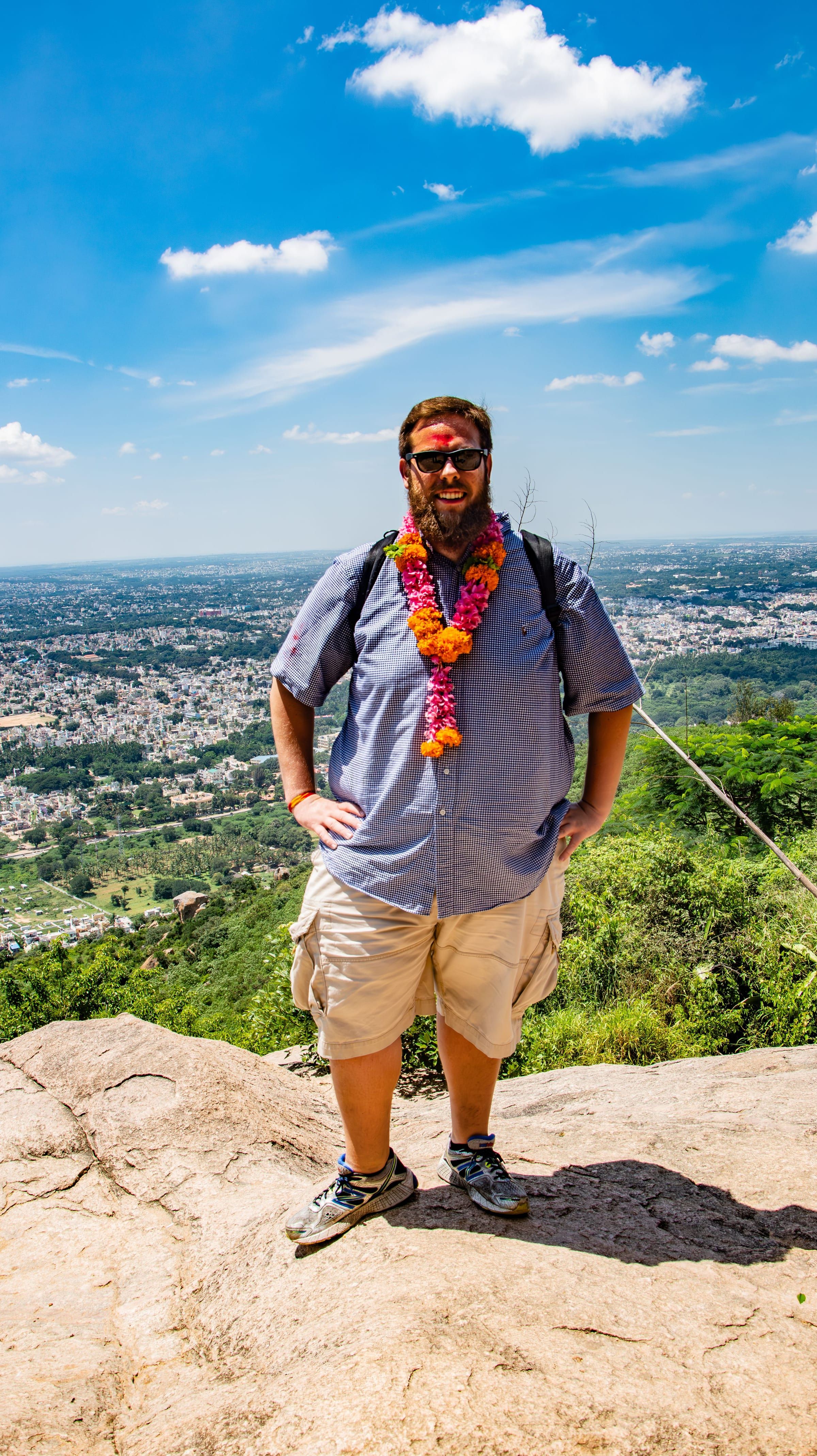 Friend in a flower garland on a rock overlook above Mysore